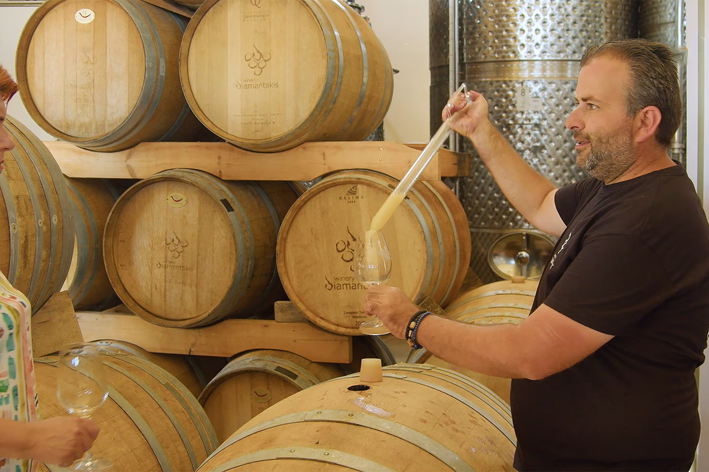 PhotonHub - Man pipettes wine from a barrel to taste it